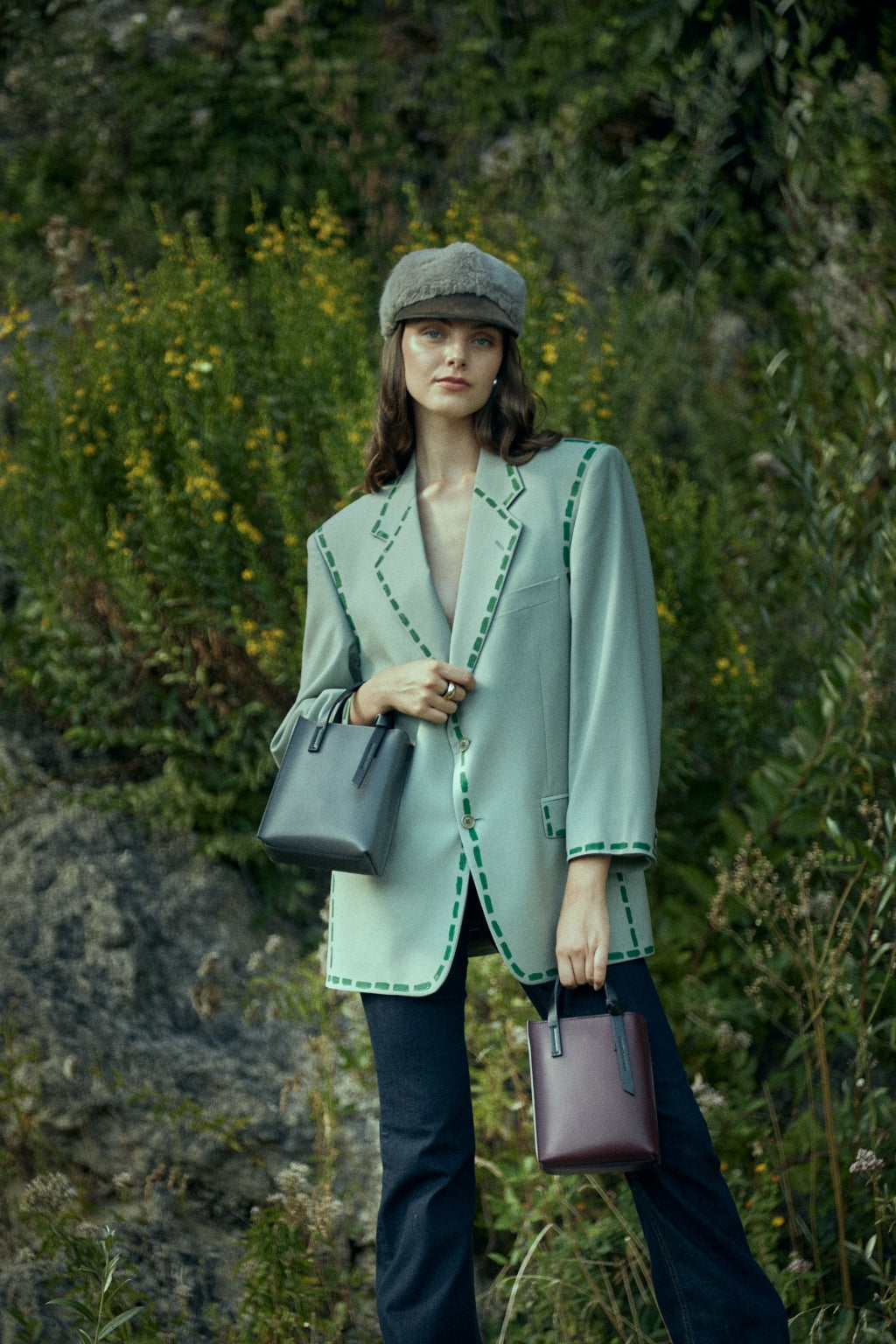 Woman wearing a stylish green blazer and hat outdoors, carrying fashionable handbags