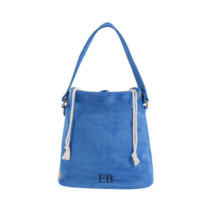 Blue suede drawstring bucket bag with adjustable shoulder strap and white rope accents