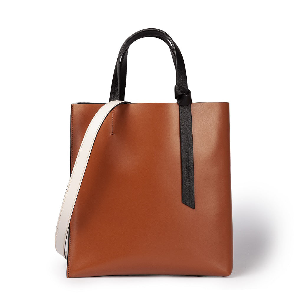 Brown leather tote bag with black handles and white strap