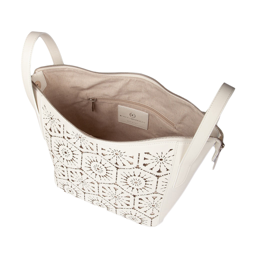 Cream handbag with intricate cut-out design and zippered interior pocket