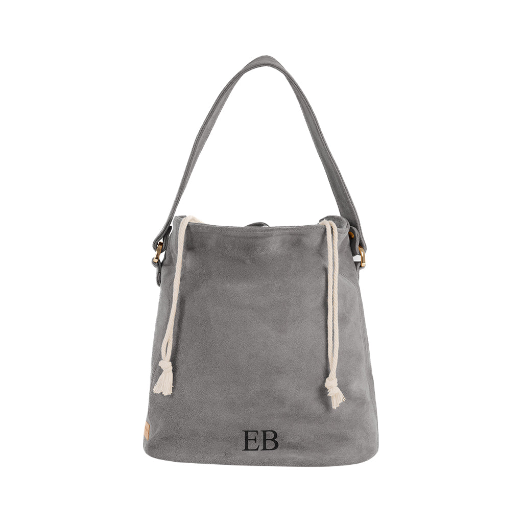 Gray suede bucket bag with drawstring closure and initials EB embroidered at the bottom
