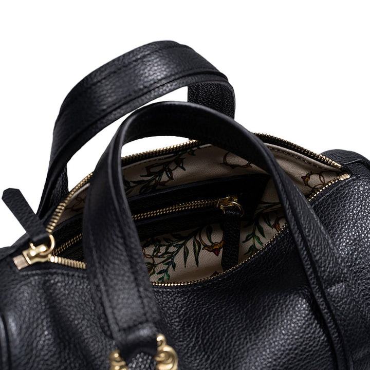 Close-up of a black leather handbag with floral interior lining and gold zipper