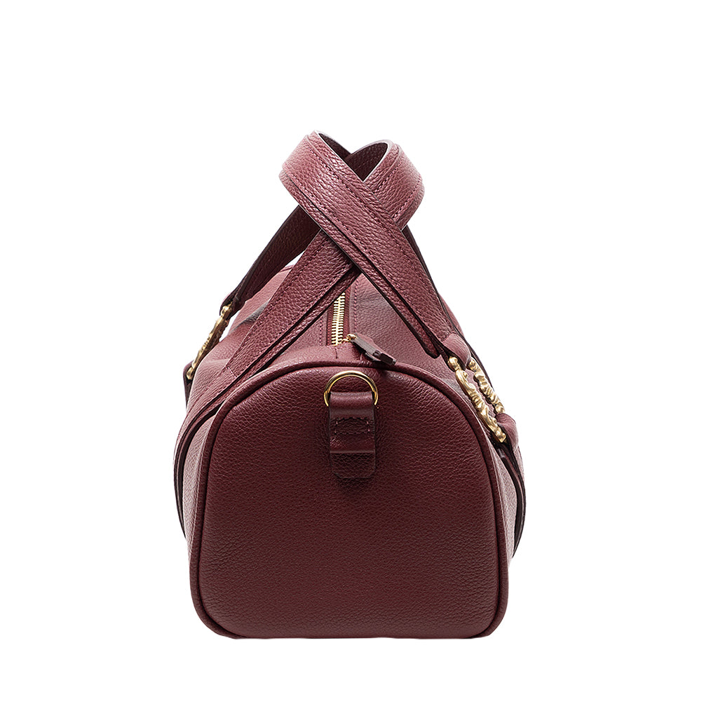 Side view of a maroon leather handbag with a gold zipper and adjustable strap