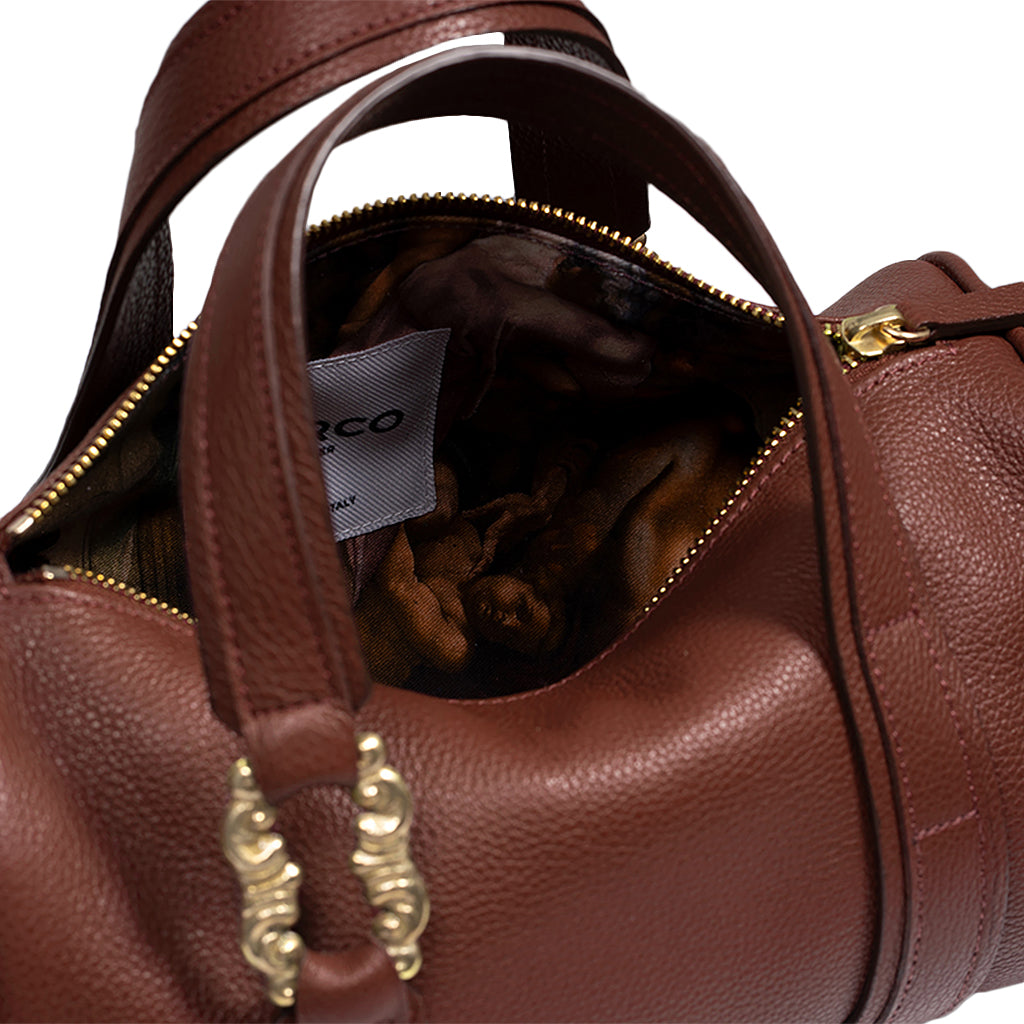 Brown leather handbag with gold hardware, showing an open zipper revealing an interior with artistic print