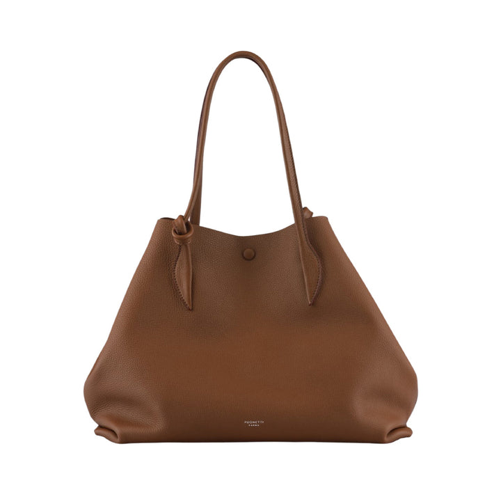 Brown leather tote bag with long handles and a button closure against a white background