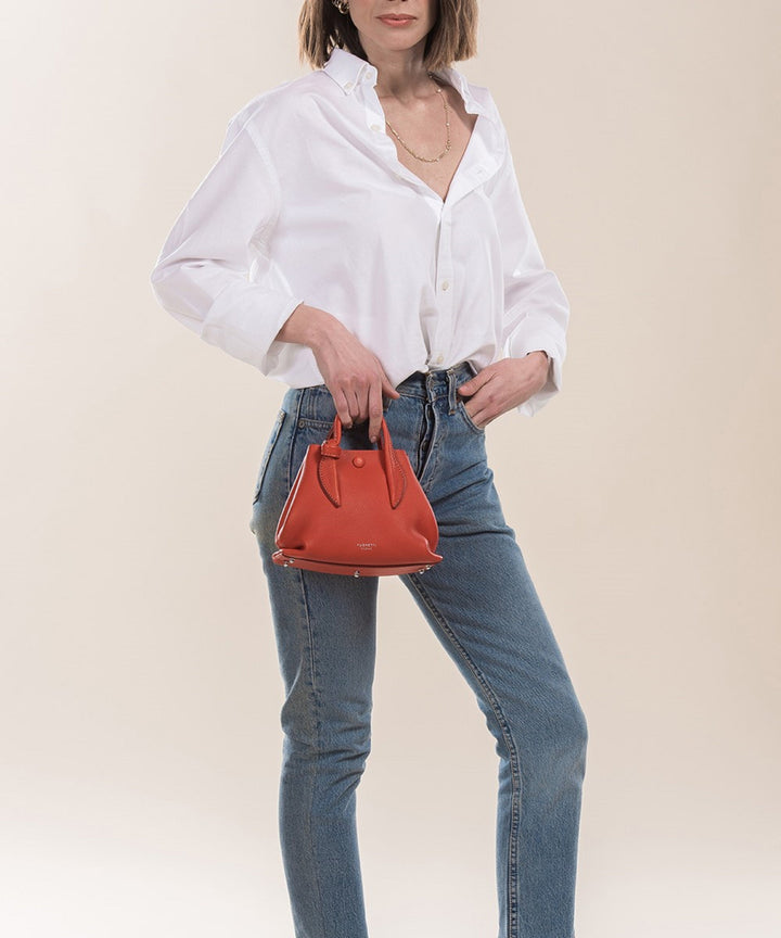 Woman in casual white shirt and blue jeans holding a red handbag