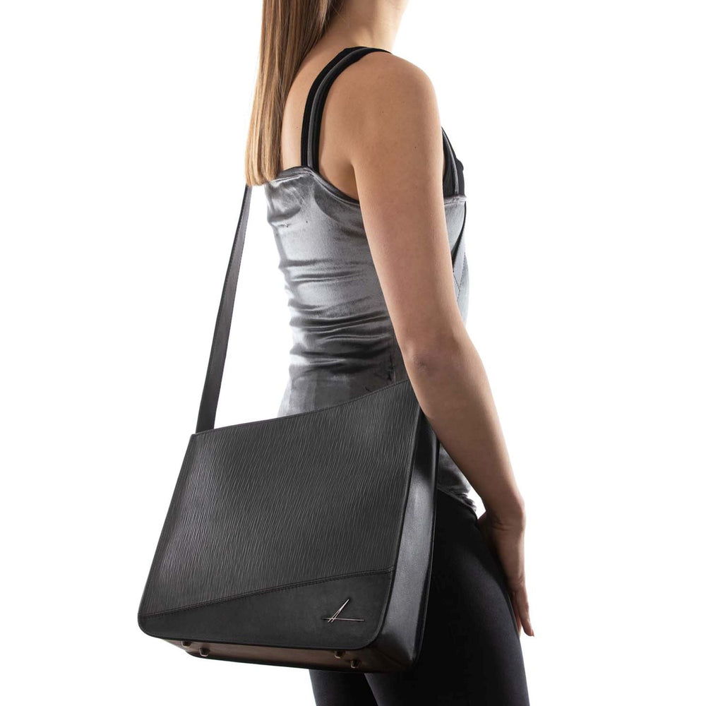 Woman wearing a silver sleeveless top carrying a black leather shoulder bag