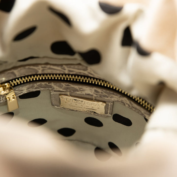 Close-up of a polka-dotted interior of a designer handbag with a gold zipper and brand label