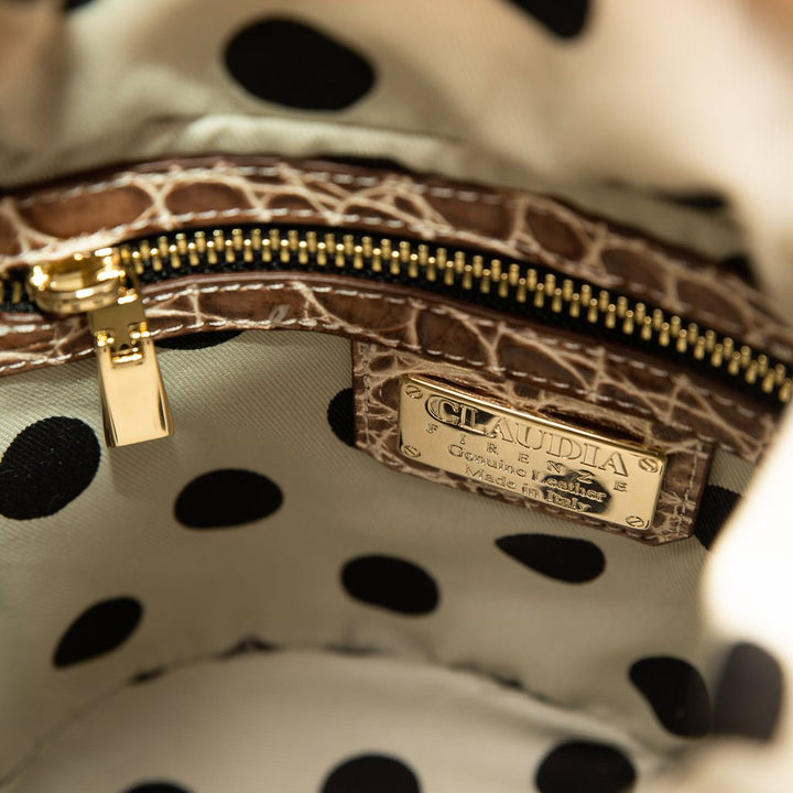 Close-up of a polka-dotted handbag interior with a branded metal label and a gold zipper