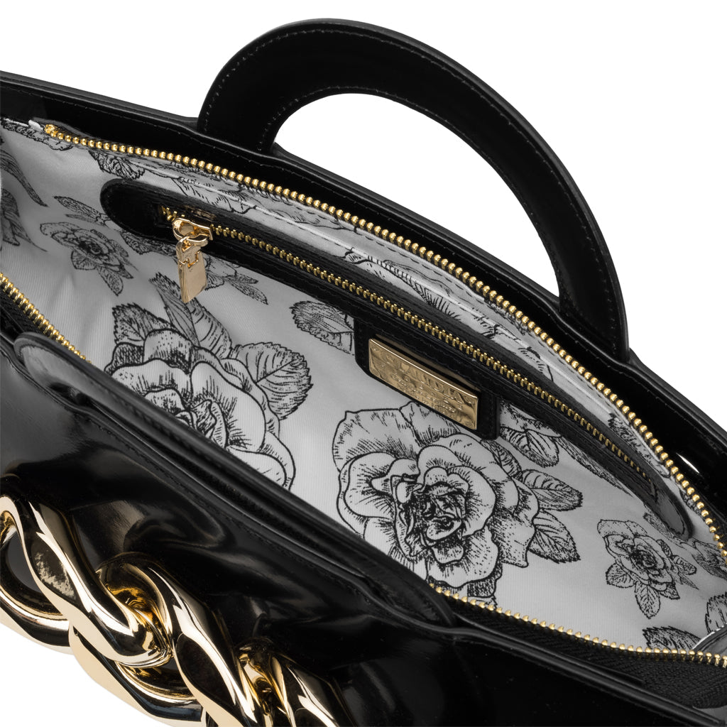 Close-up view of a black leather handbag with gold chain detailing and floral-patterned lining