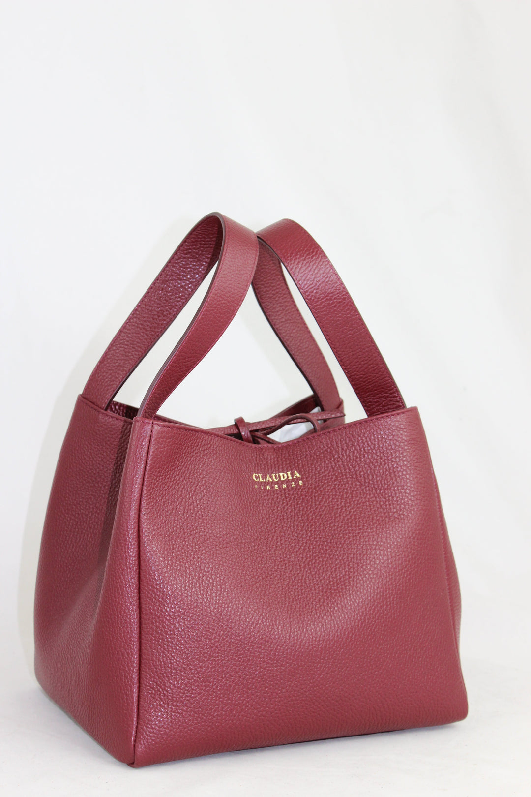 Maroon leather handbag with gold Claudia branding on white background