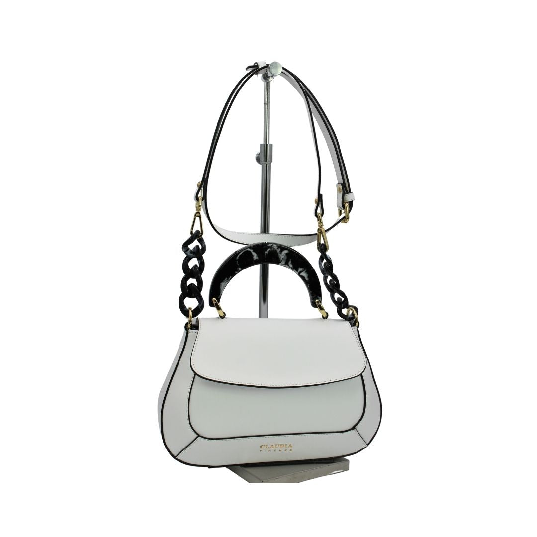 White designer handbag with black accents and shoulder strap on display stand