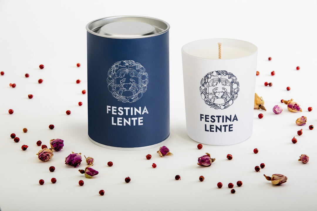 Luxury Festina Lente candles with botanical design surrounded by dried flowers and peppercorns