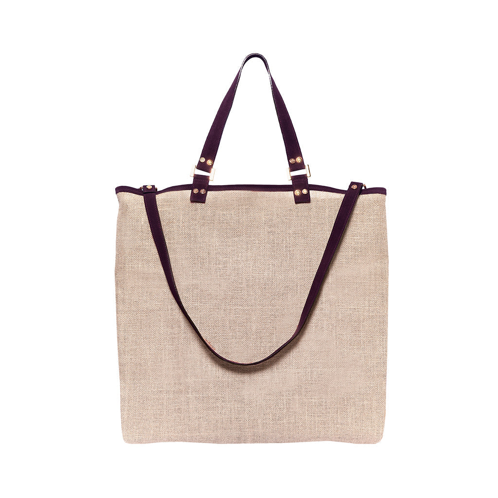 Beige canvas tote bag with dark brown leather handles and adjustable shoulder strap