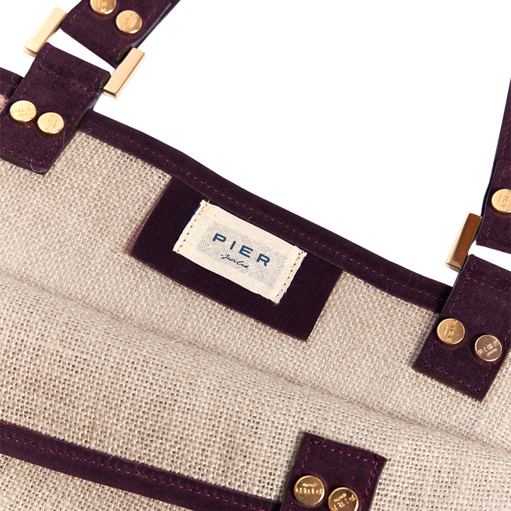 Close-up view of a stylish beige and purple handbag with branded tag and metallic studs