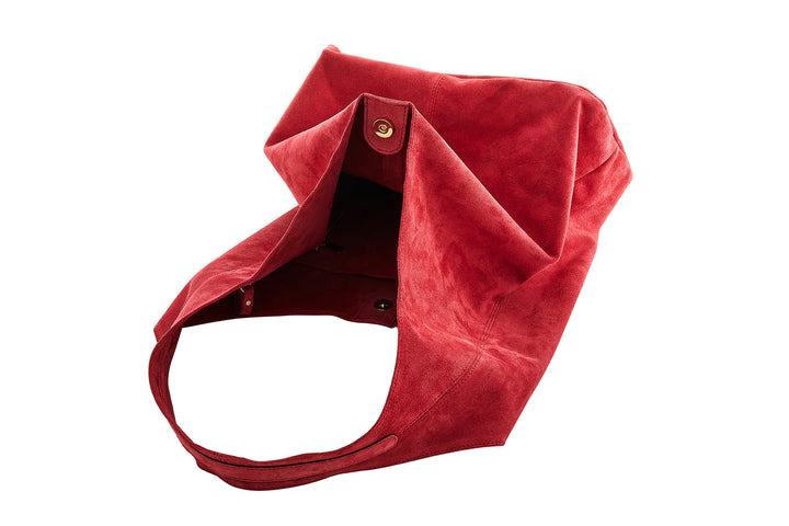 Soft red suede handbag with button closure laying open on a white background