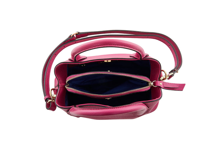 Top view of an open pink leather handbag with multiple compartments and a shoulder strap