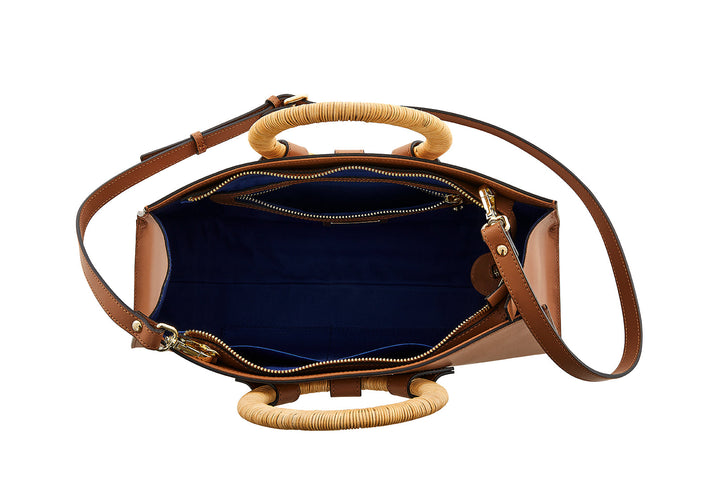 Top view of an open brown leather handbag with a woven handle and blue interior lining