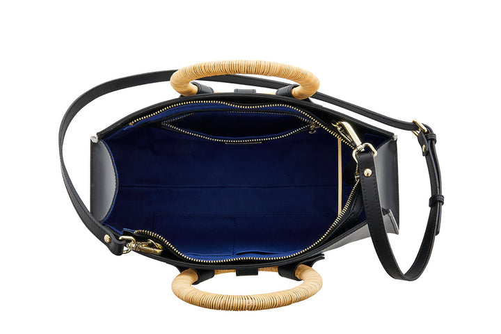 Top view of a black handbag with bamboo handles, open to show blue interior and zipper compartments