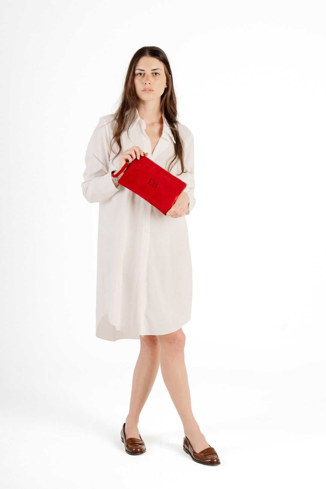Woman in white dress holding red clutch purse on white background