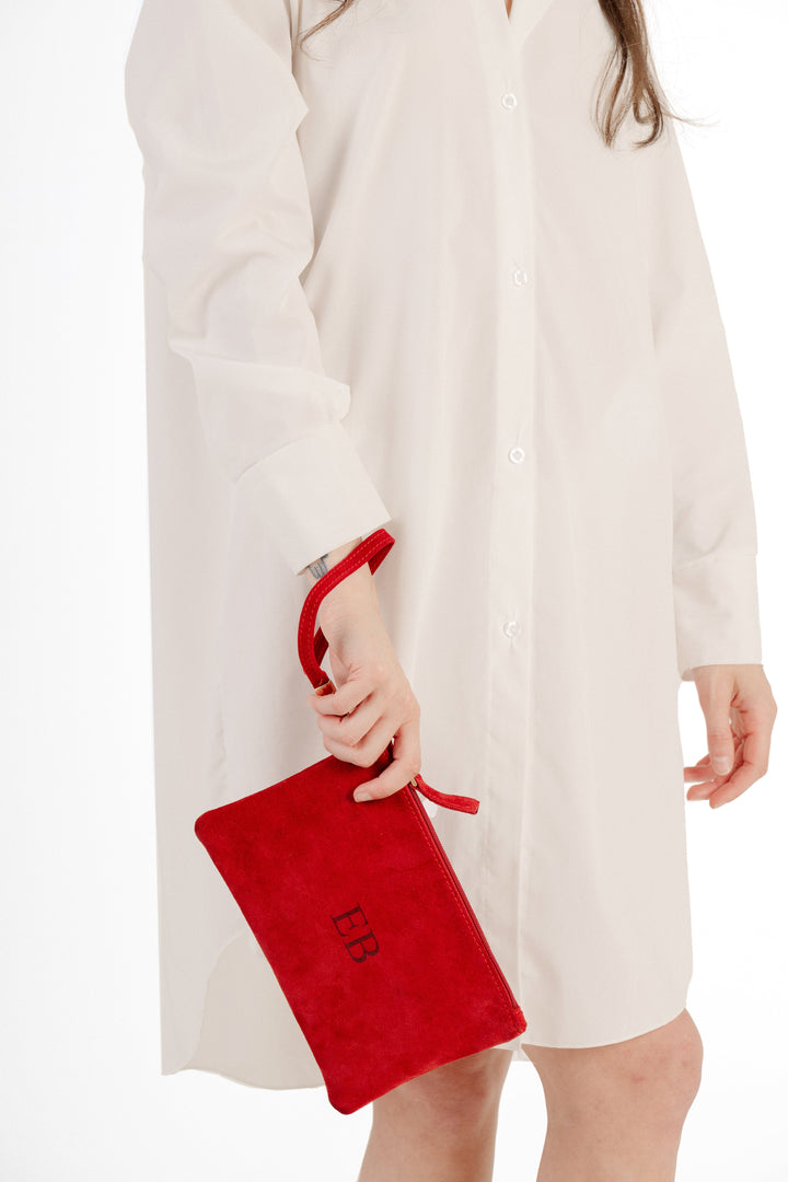 Woman in white dress holding a red clutch with initials EB