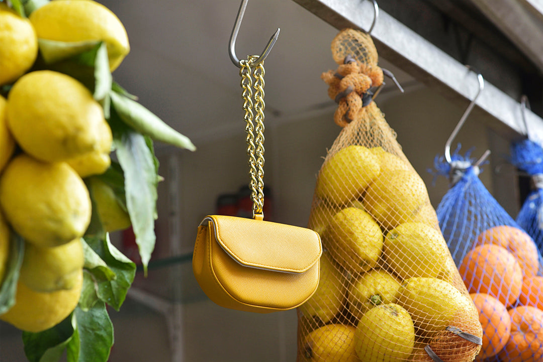 Yellow purse hanging among bags of lemons and oranges at a market