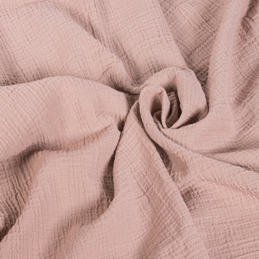 Close-up of soft pink textured fabric, neatly gathered in a spiral pattern