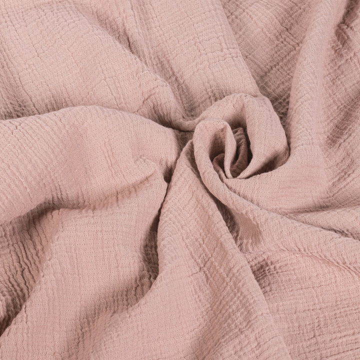 Close-up of soft pink textured fabric, neatly gathered in a spiral pattern