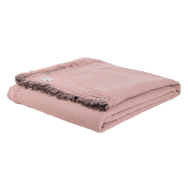 Soft pink fringed blanket folded neatly