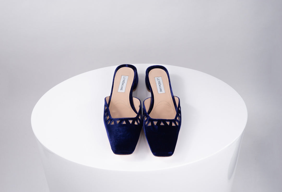 Elegant navy blue velvet slip-on shoes with geometric cut-out design on a white surface