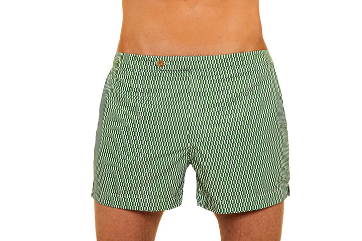 Green patterned swim trunks worn by a man on a white background