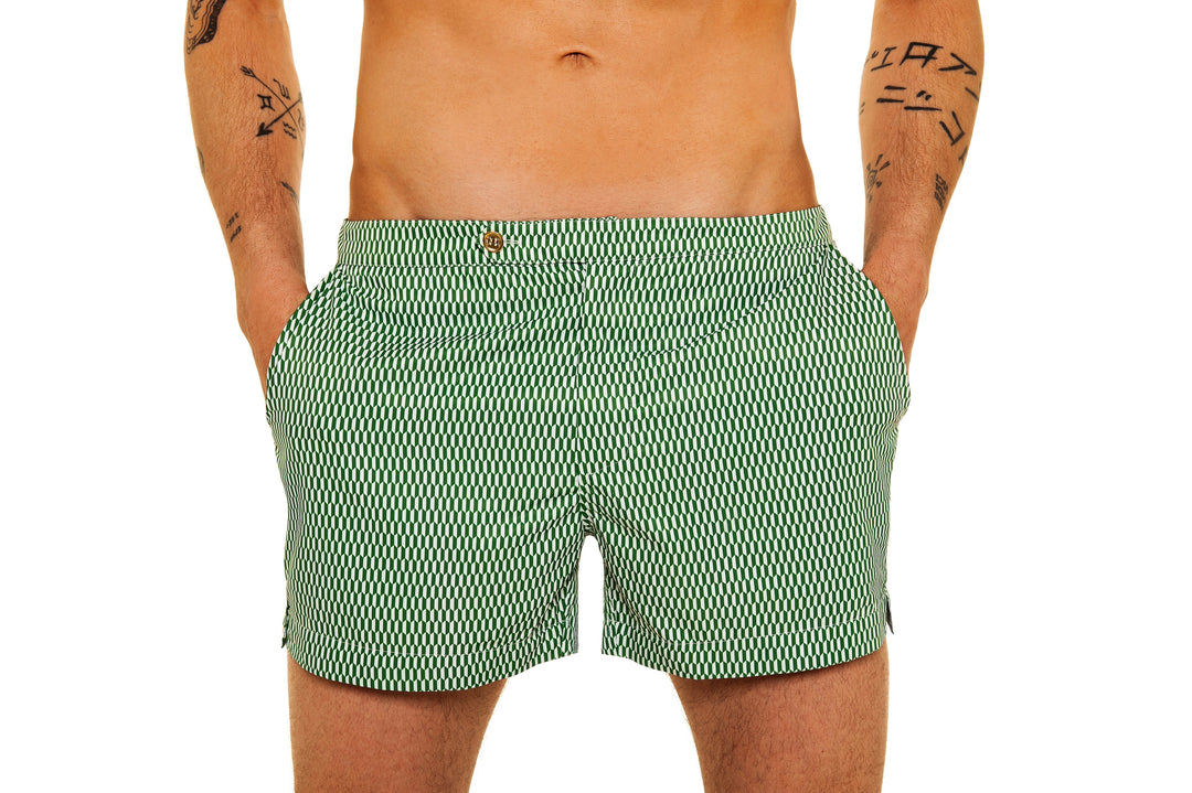 Man wearing green patterned swim shorts with hands in pockets