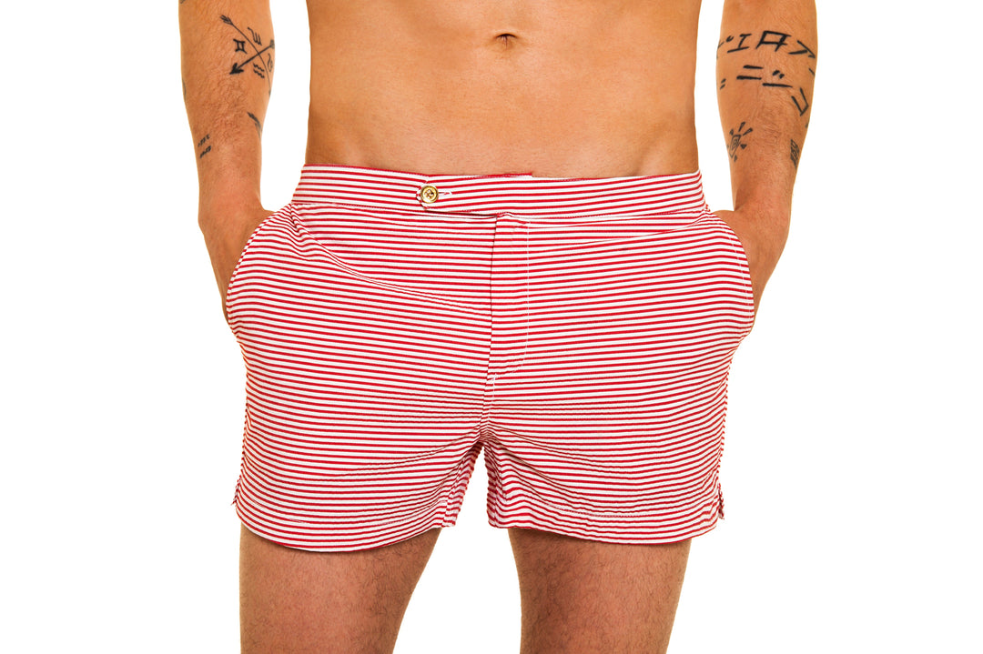 Red and white striped men's swim trunks with tattoos on arms