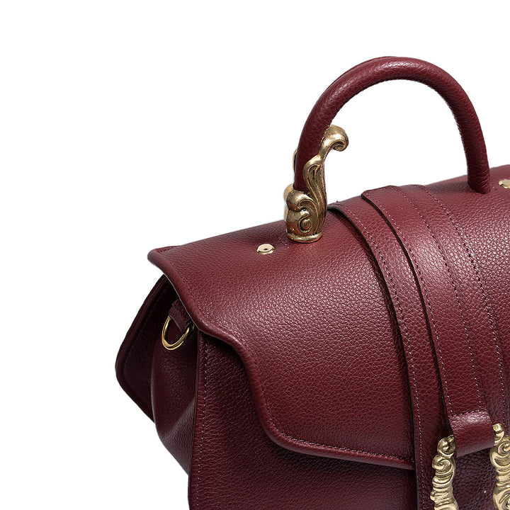 Close-up of a luxurious maroon leather handbag with ornate gold hardware