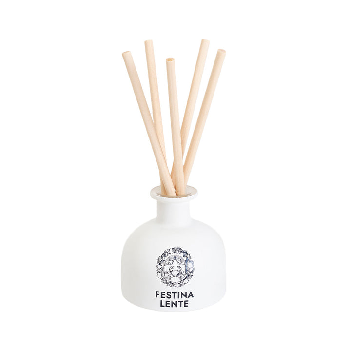 White diffuser bottle with wooden reed sticks and Festina Lente label