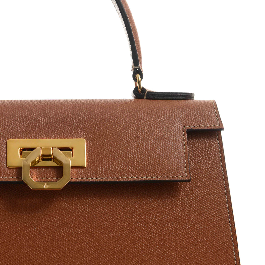 Close-up of a brown leather handbag with a gold clasp and handle