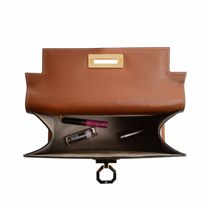 Brown leather handbag open with view of interior and makeup items