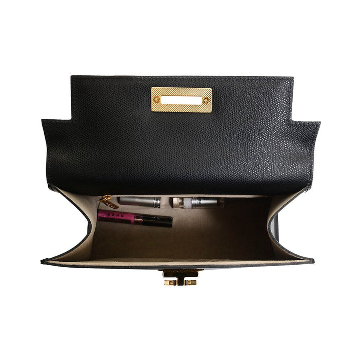 Open black leather handbag showing interior with makeup items