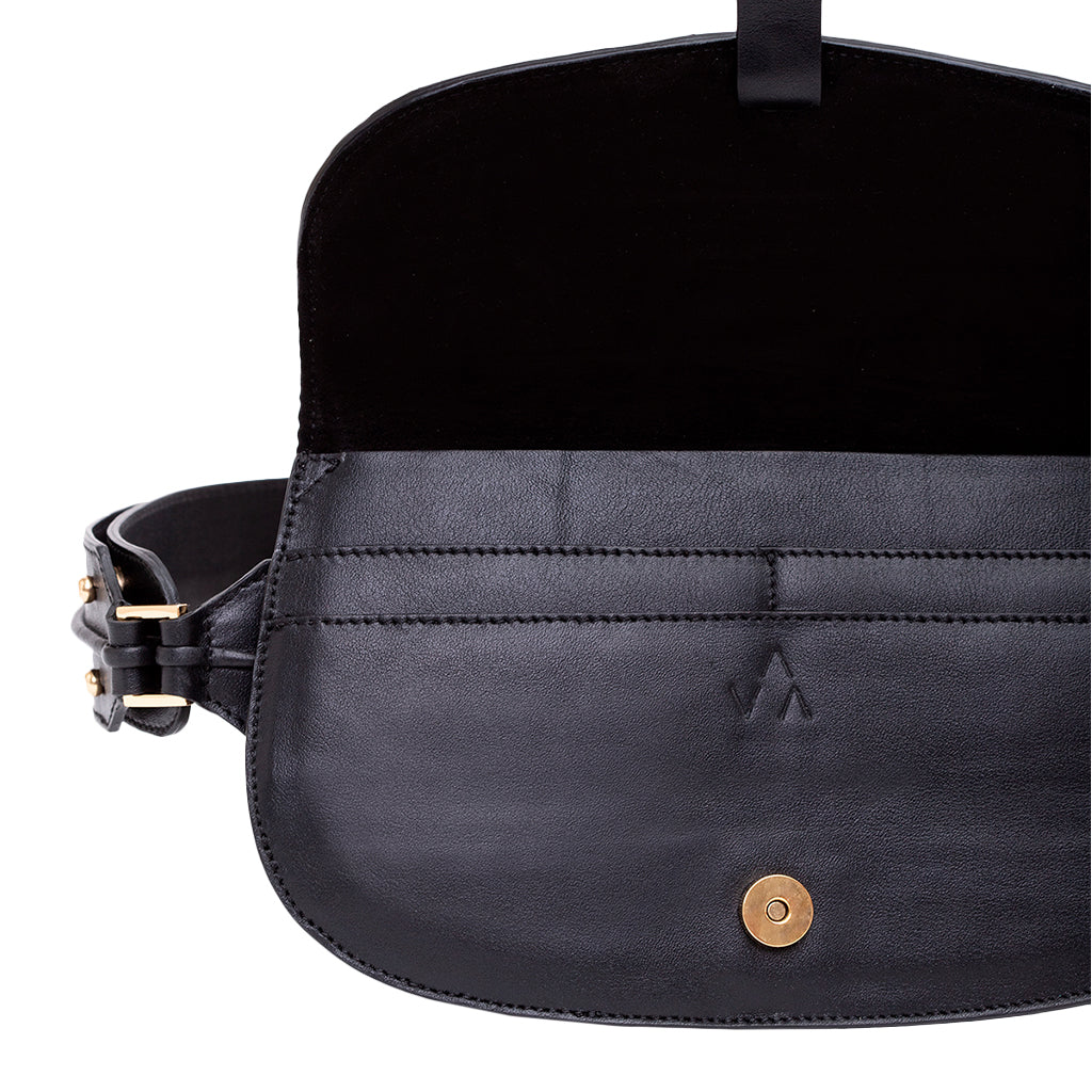 Black leather crossbody bag with open flap showing interior compartments and brass button closure