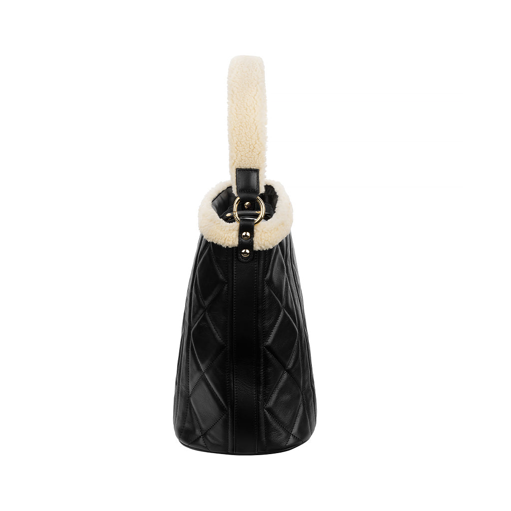 Side view of a black quilted leather handbag with a faux fur handle