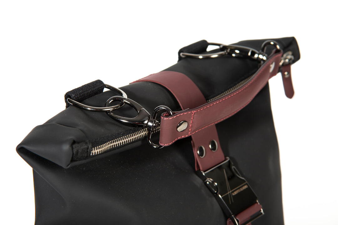Close-up of a stylish black and burgundy leather bag with metal buckles and zippers