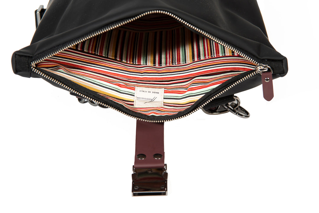 Open black leather bag with colorful striped interior lining and silver zipper