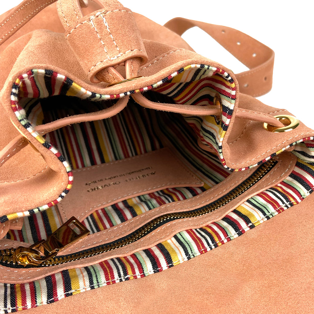 Open tan suede backpack with colorful striped interior and zippered pocket