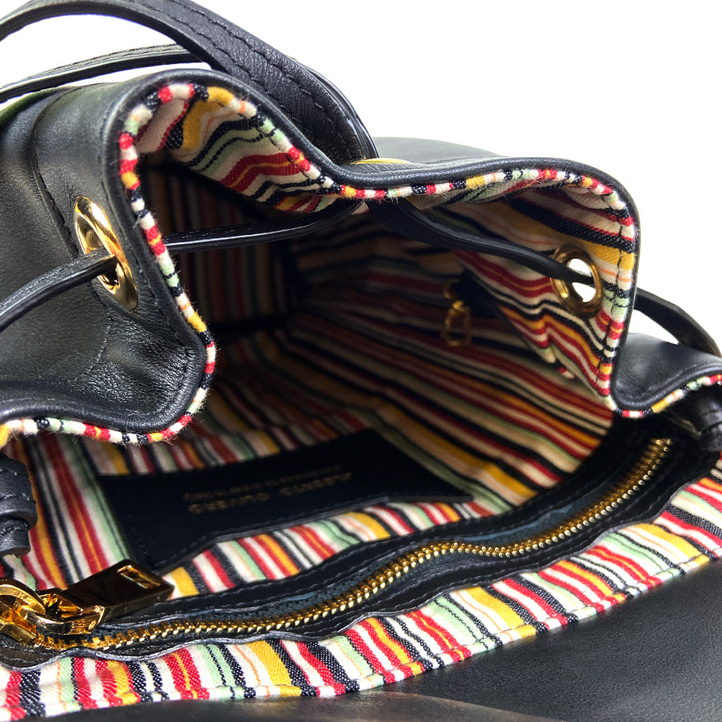 Open black leather handbag revealing a colorful striped fabric interior with a zippered pocket