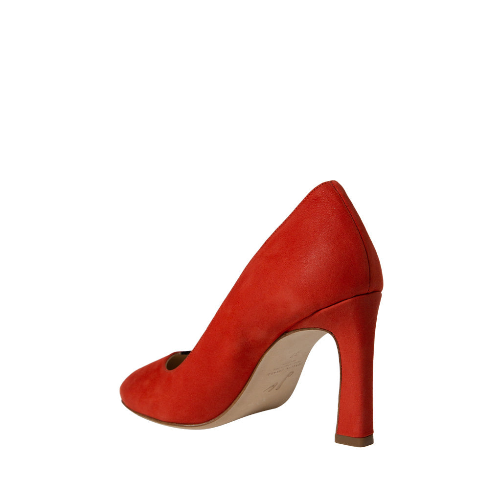 Red high-heeled pump shoe with pointed toe and suede finish on white background