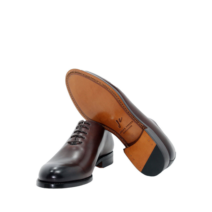 Elegant polished brown leather dress shoes with black sole and laces