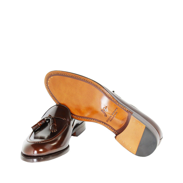 Brown leather tassel loafers with wooden soles on a white background