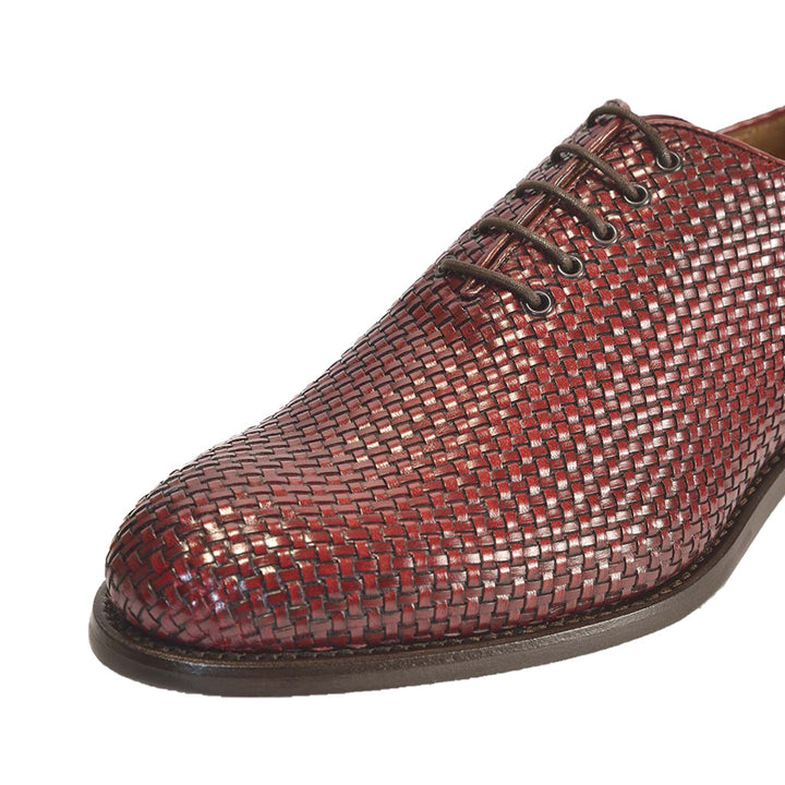 Close-up of a men's burgundy woven leather dress shoe with laces