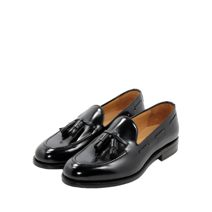 Black leather tassel loafers on white background