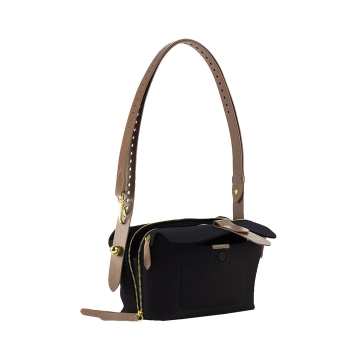 Black designer handbag with adjustable tan leather strap and gold zipper